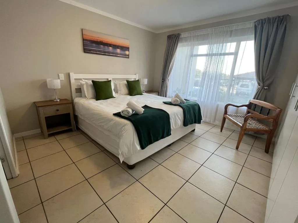 Spacious bedroom with double bed, green accents, and large windows overlooking the town