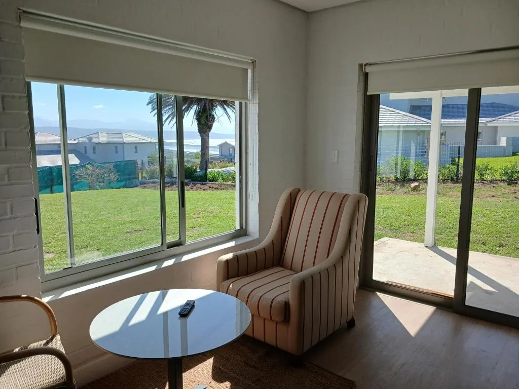 Modern lounge with striped armchair, round table, coastal views through large windows