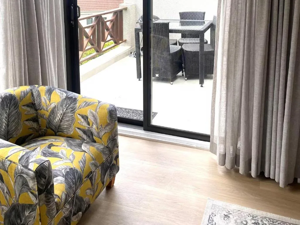 Modern lounge with patterned yellow chair opening onto deck area