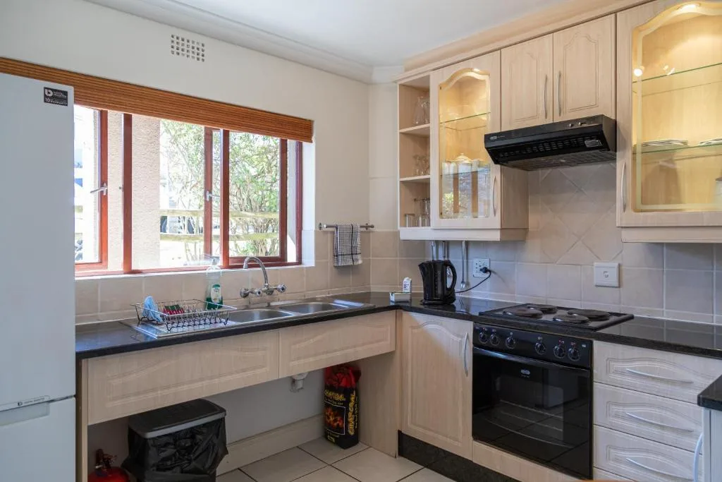 Cream cabinetry kitchen with black gas range and stainless sink