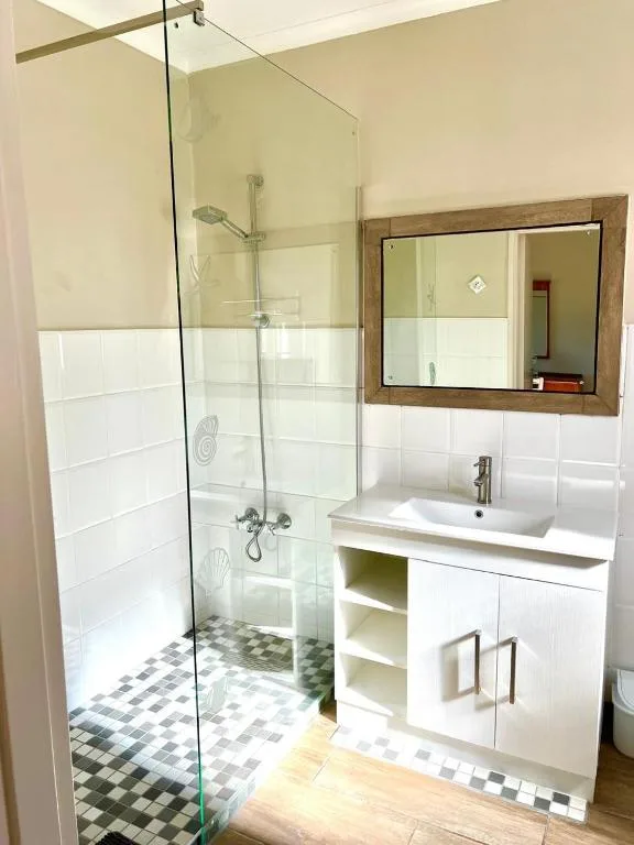 Modern bathroom with walk-in shower, white vanity, and framed mirror