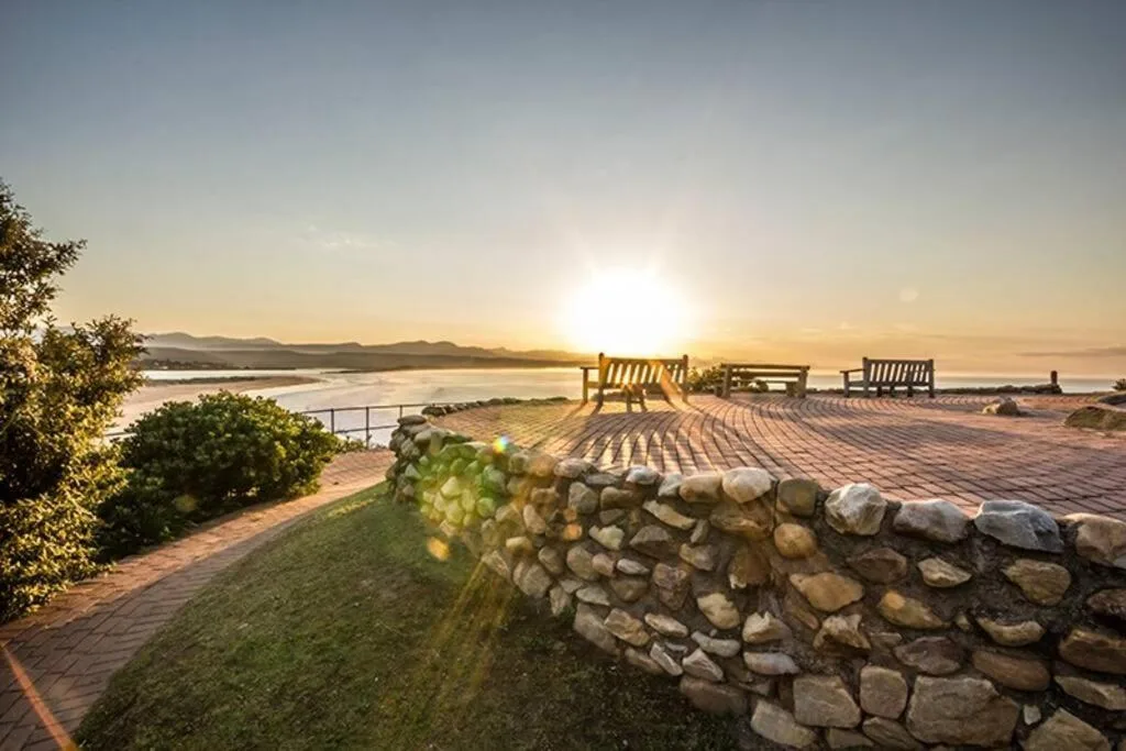 Sunrise over lagoon with wooden benches and manicured garden deck