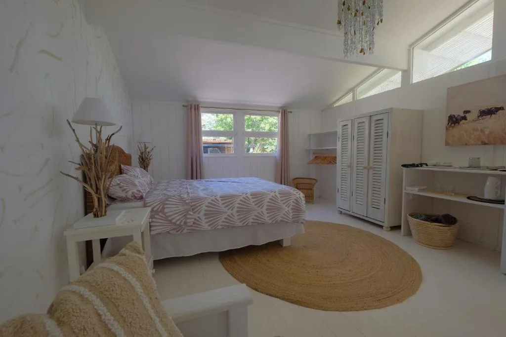 Bright bedroom with queen bed, white wardrobe, and natural light from windows