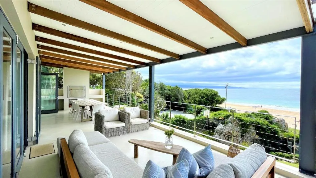 Covered outdoor deck with ocean and beach views from seating area
