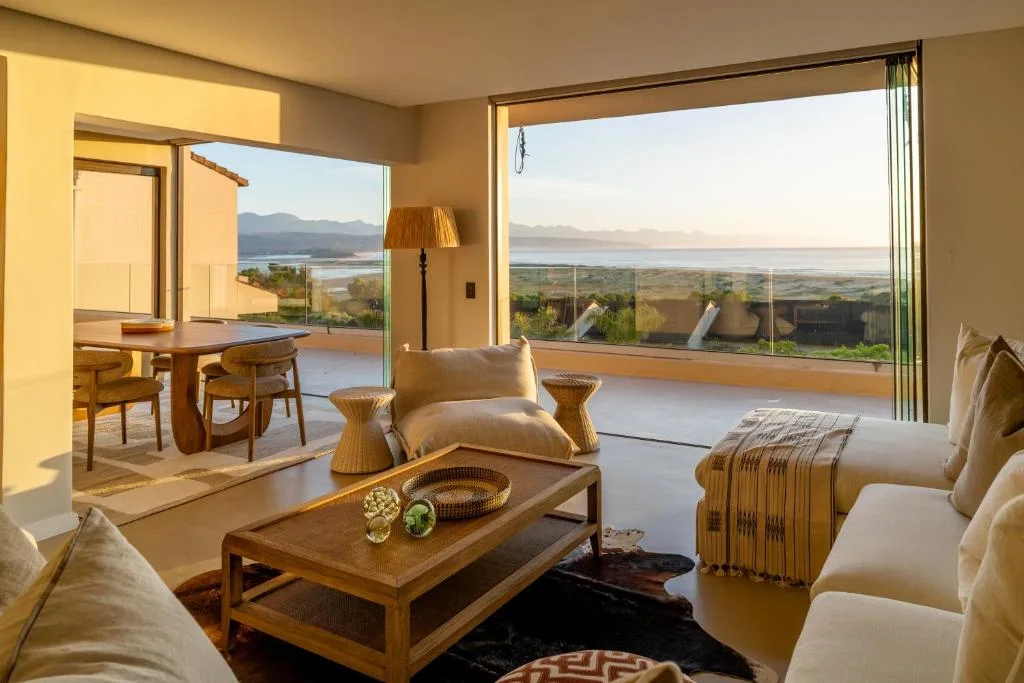 Spacious lounge with cream sofas overlooking lagoon and mountains through large windows