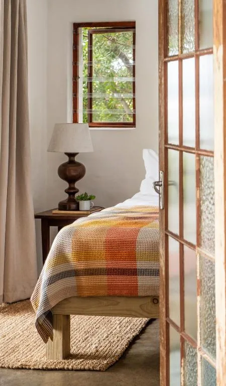 Cozy bedroom with single bed, wooden nightstand, and warm natural light from windows