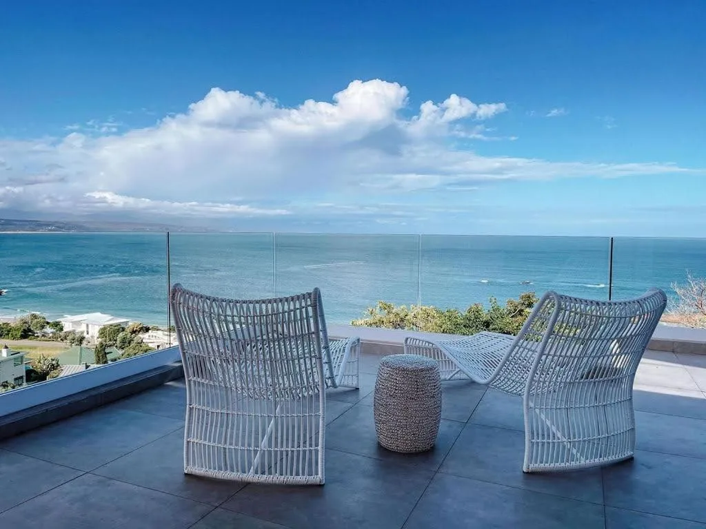 Coastal deck with woven chairs overlooking turquoise ocean and sky