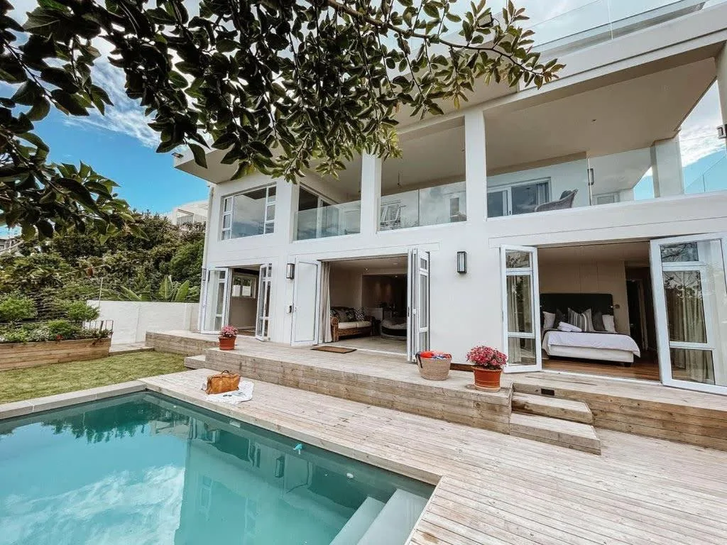 Modern white villa with pool, wooden deck, and manicured garden
