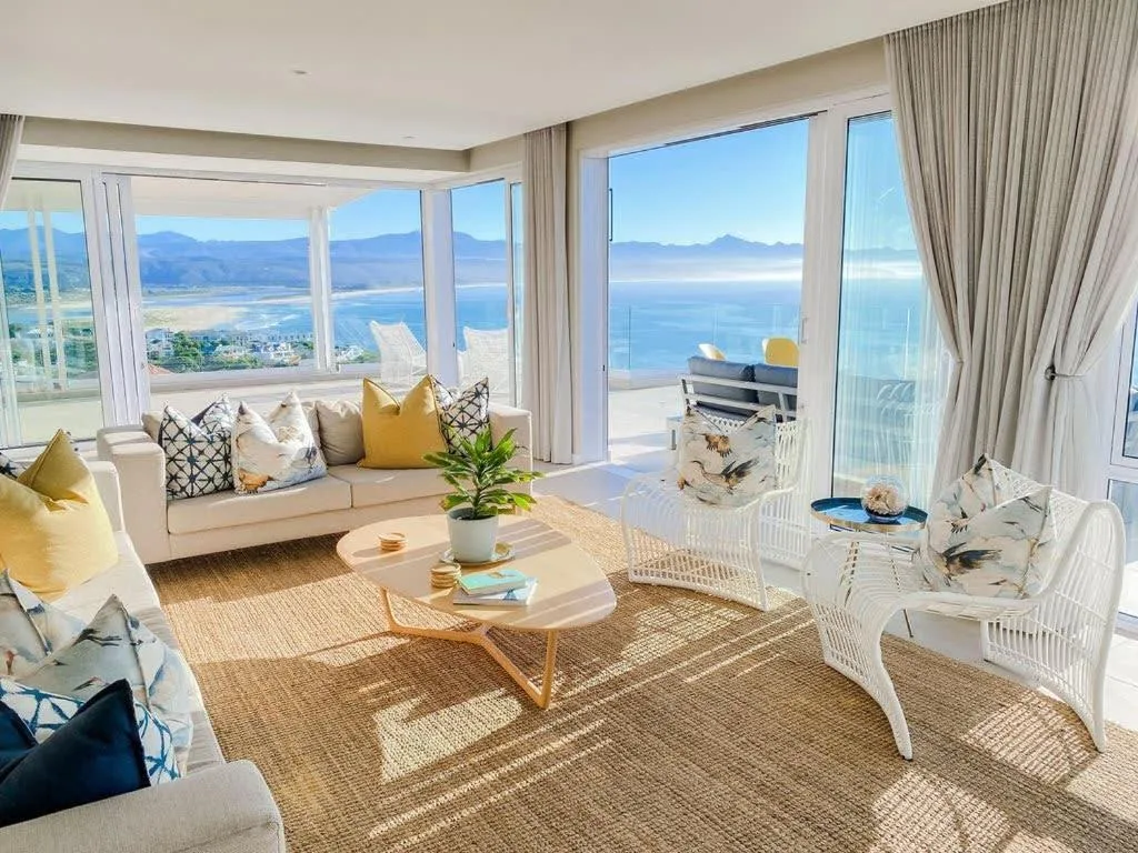 Bright lounge with panoramic ocean and mountain views through floor-to-ceiling windows