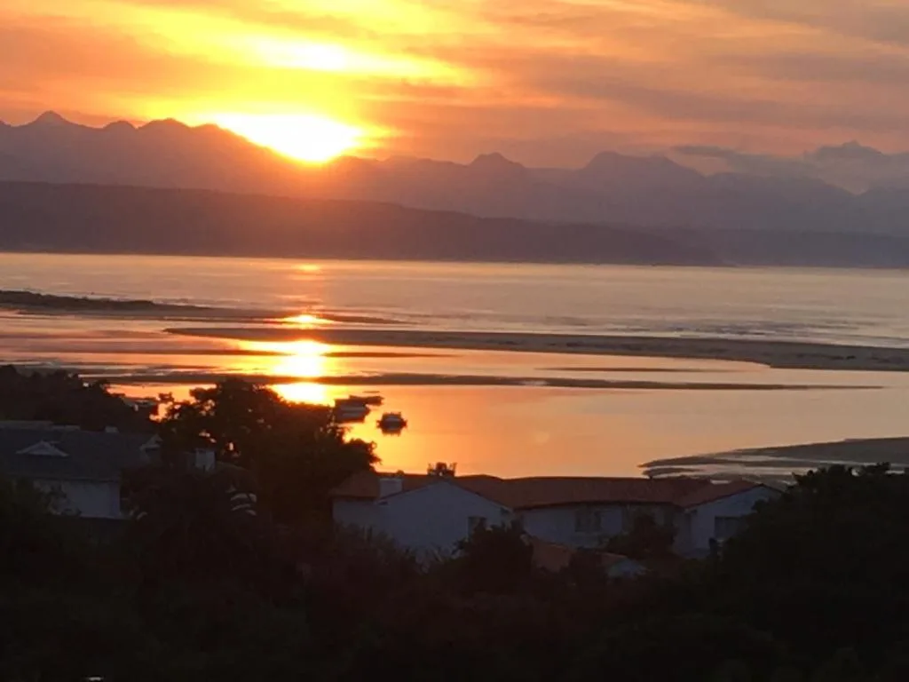 Golden sunset over lagoon with mountains and coastal houses silhouetted