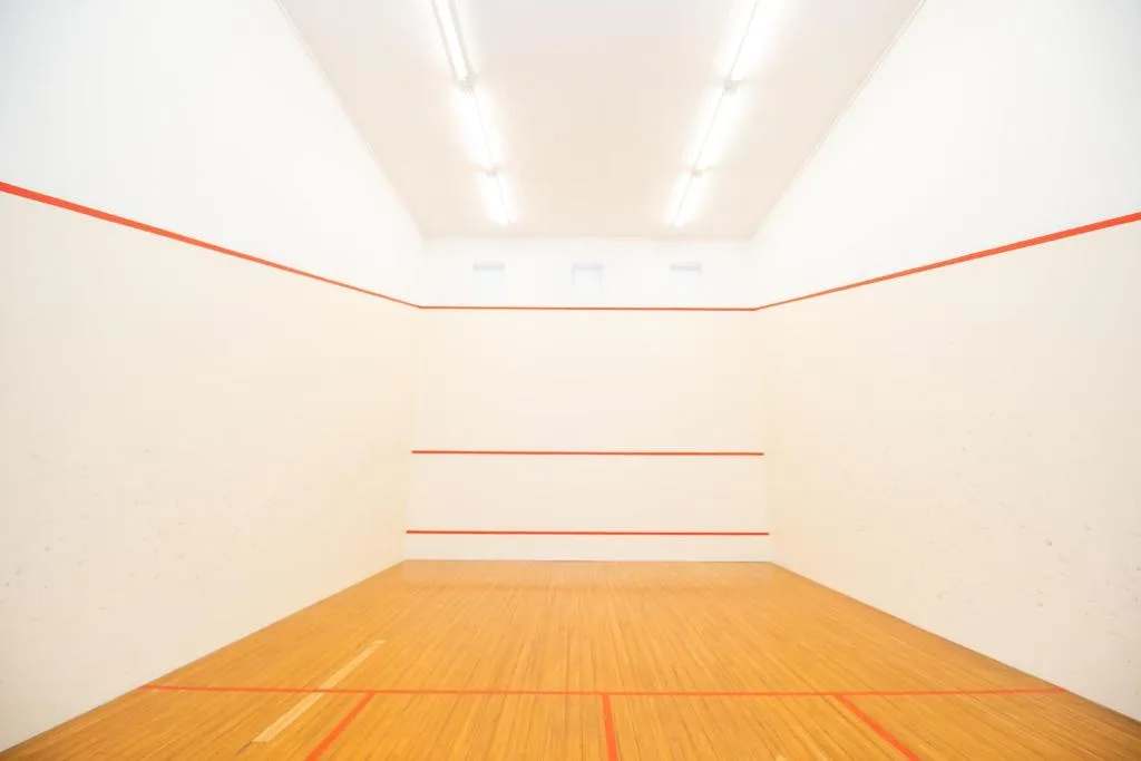 Modern squash court with wooden floor and white walls