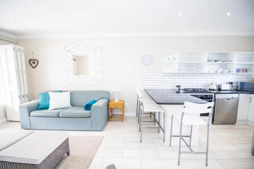 Bright open-plan lounge with gray sofa and kitchen visible in background