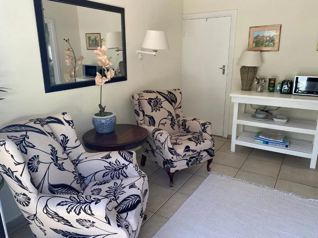 Bright lounge with patterned armchairs, round side table, and large mirror