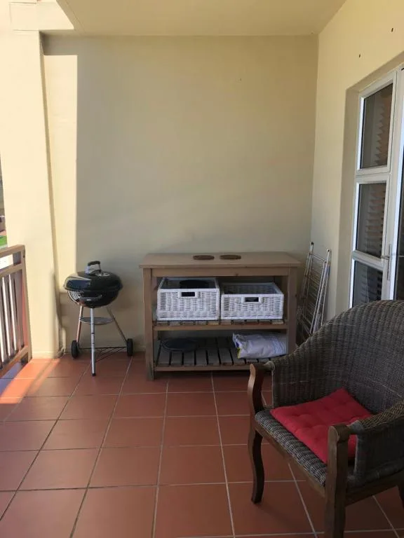 Covered patio area with braai grill, storage, and seating overlooking garden