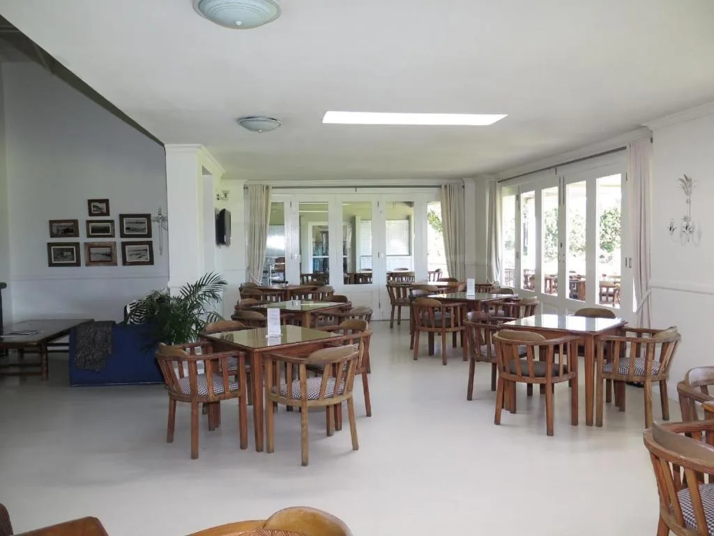 Spacious dining area with multiple wooden tables and chairs opening to deck