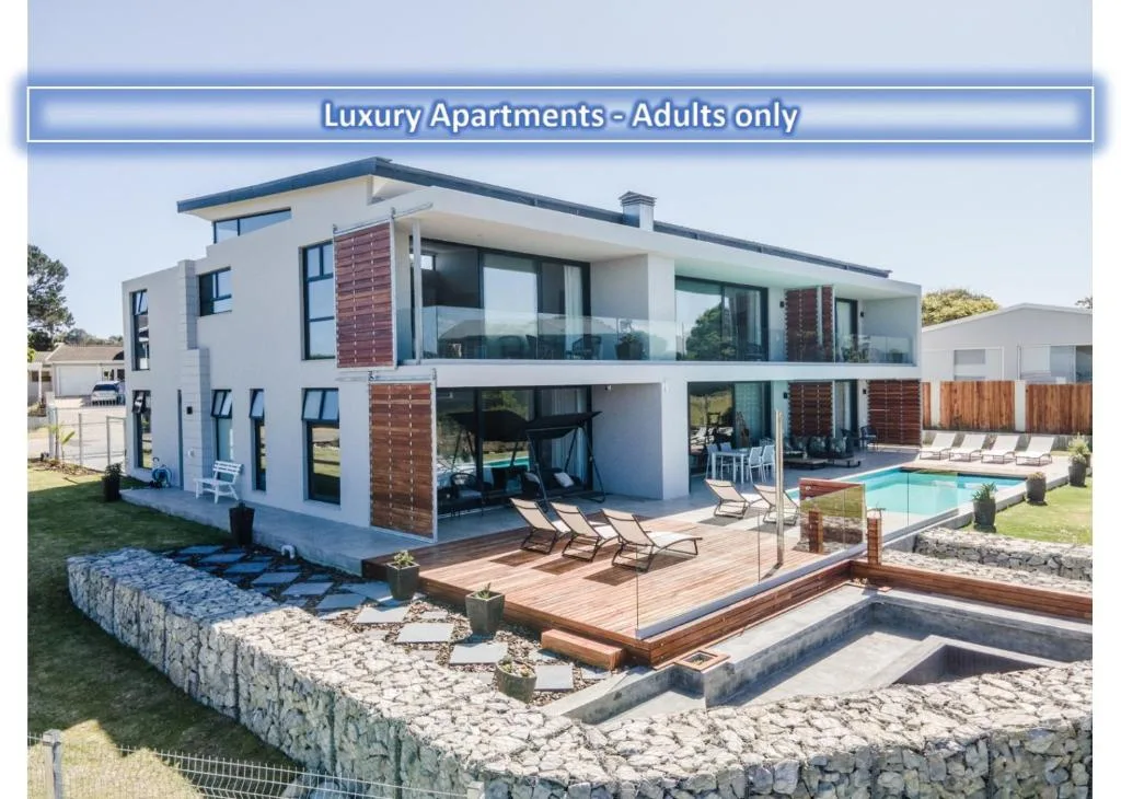 Modern white luxury apartment with pool, deck chairs, and manicured gardens