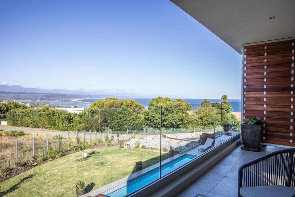 Expansive coastal and mountain vista from elevated deck with pool