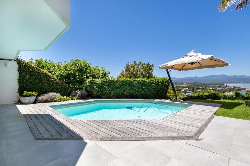 Turquoise swimming pool with wooden deck and lagoon view umbrella