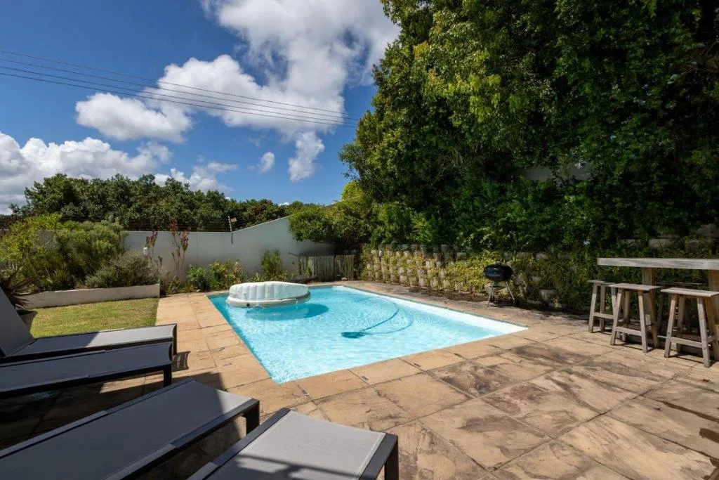 Sparkling turquoise swimming pool with spa in landscaped garden setting