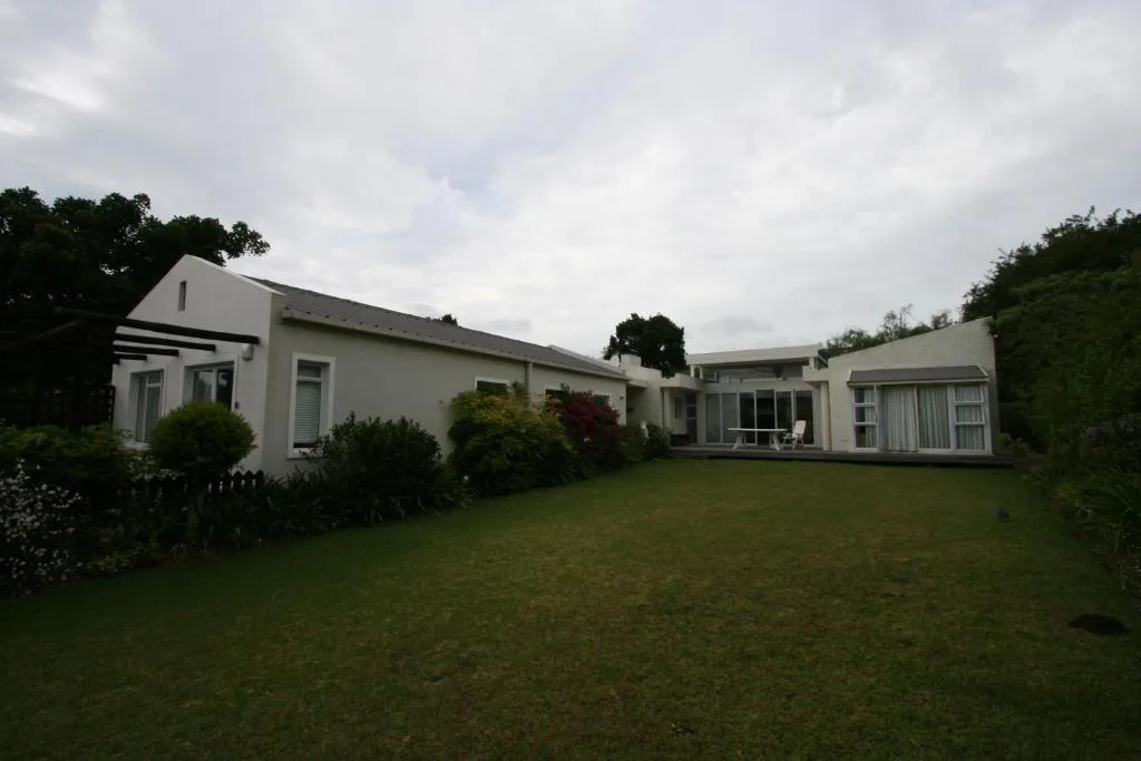 White modern home with manicured lawn and surrounding green landscaping