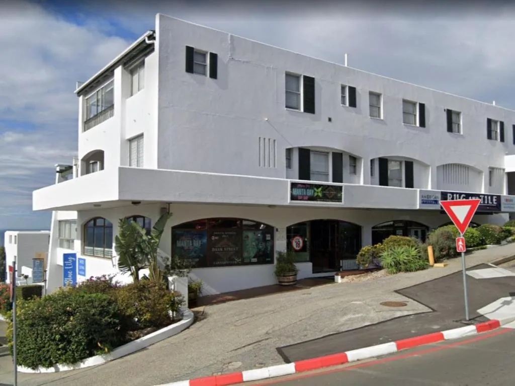 White modernist apartment building with ground floor retail and street frontage