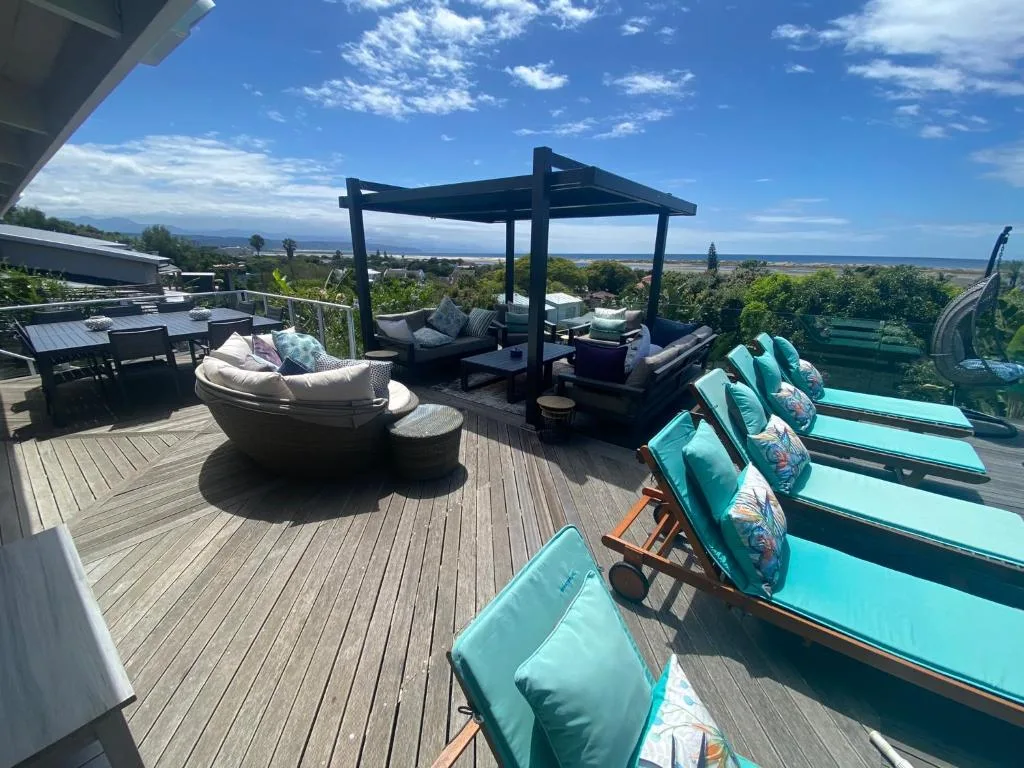 Expansive wooden deck with lounge seating, pergola, and panoramic valley views
