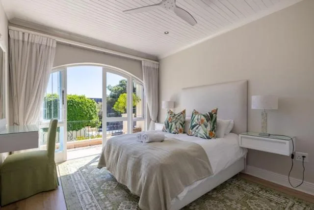 Bright bedroom with bed, garden view through arched doors, coastal decor