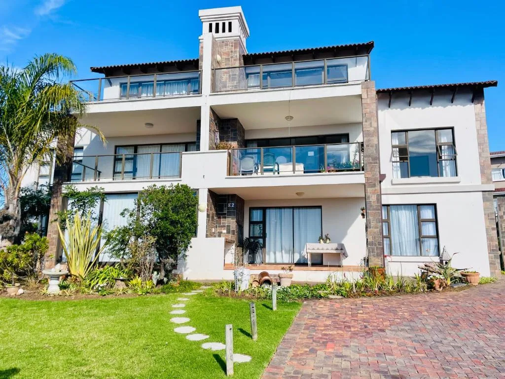 Modern multi-story white apartment building with brick accents and balconies