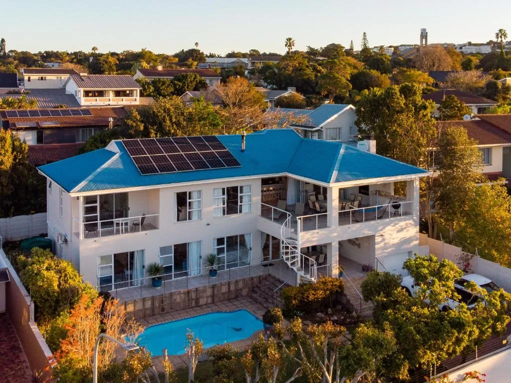 Modern white house with blue roof and solar panels overlooking pool