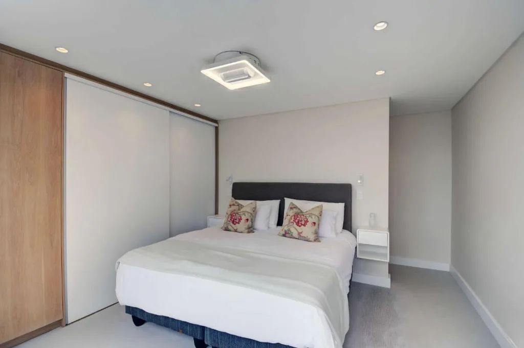 Modern bedroom with queen bed, floral pillows, built-in wardrobes, recessed lighting