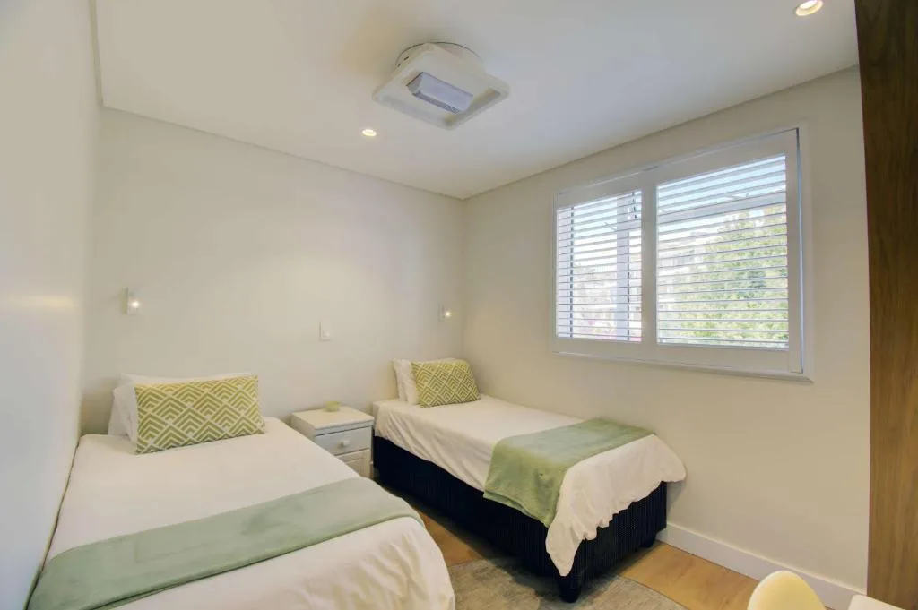 Twin bedroom with yellow accent pillows and shuttered windows