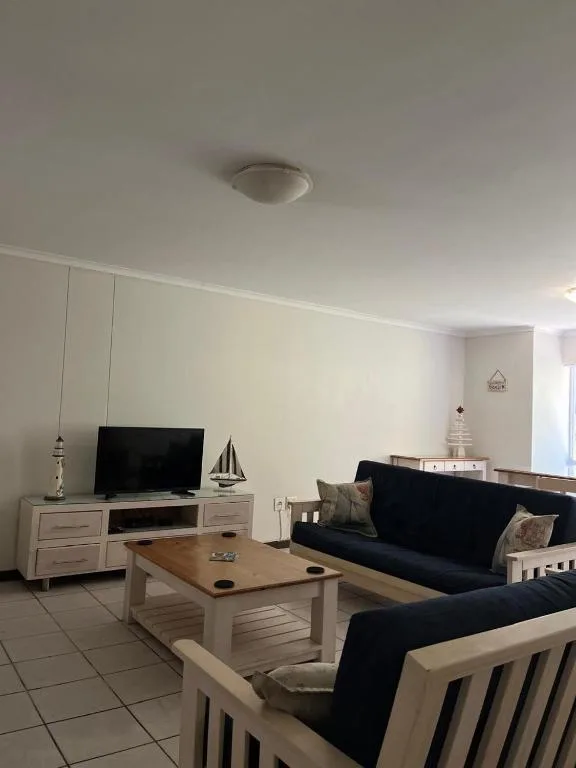 Modern living room with black sofas, wooden coffee table, and wall-mounted television