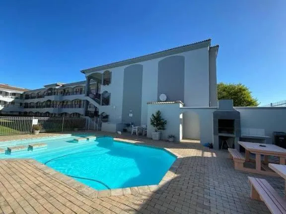 Bright turquoise swimming pool with modern white building facade backdrop