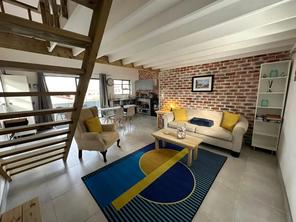 Spacious open-plan lounge with exposed brick wall and modern furnishings