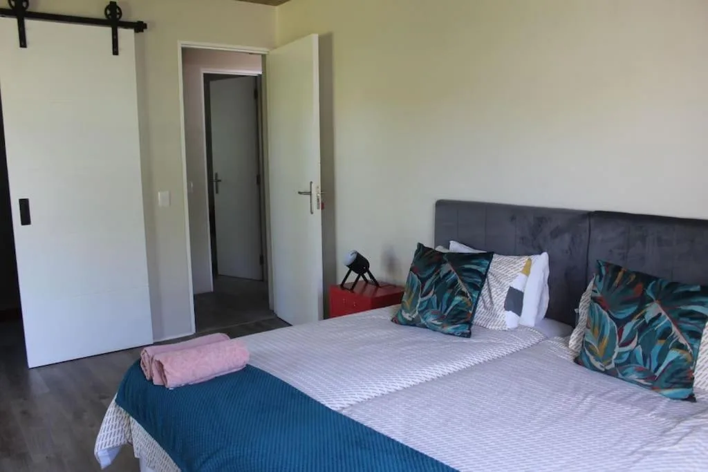 Spacious bedroom with dark upholstered headboard and colorful patterned pillows