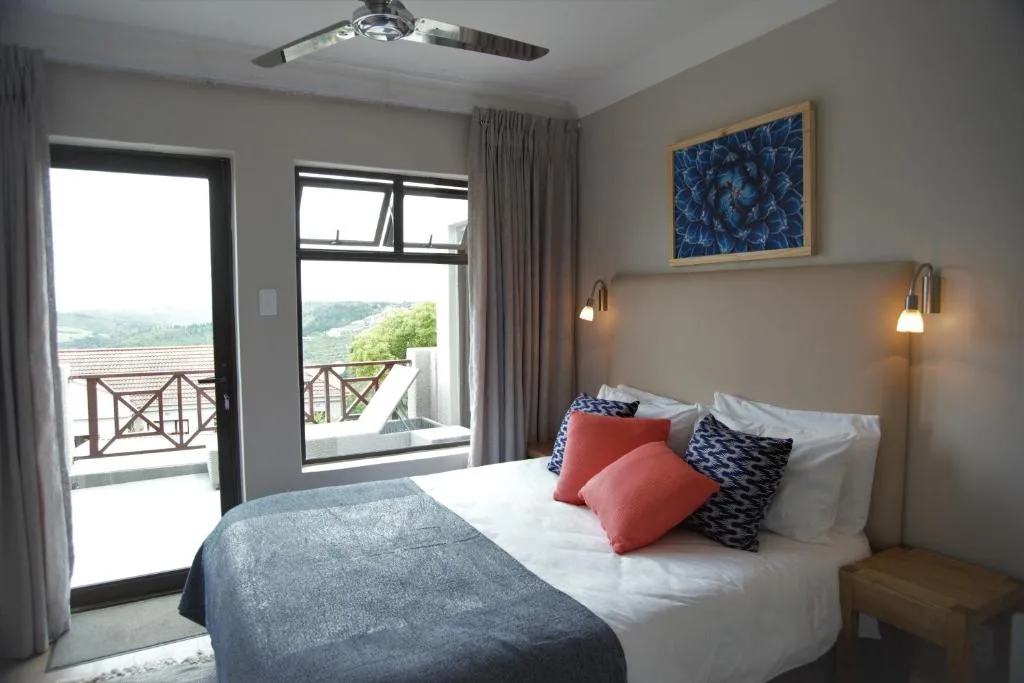 Bright bedroom with bed, colorful pillows, and scenic valley views through glass doors