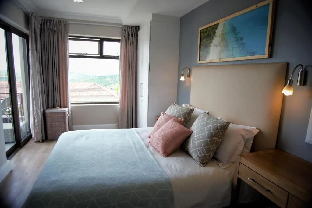 Modern bedroom with queen bed, decorative pillows, and large window views