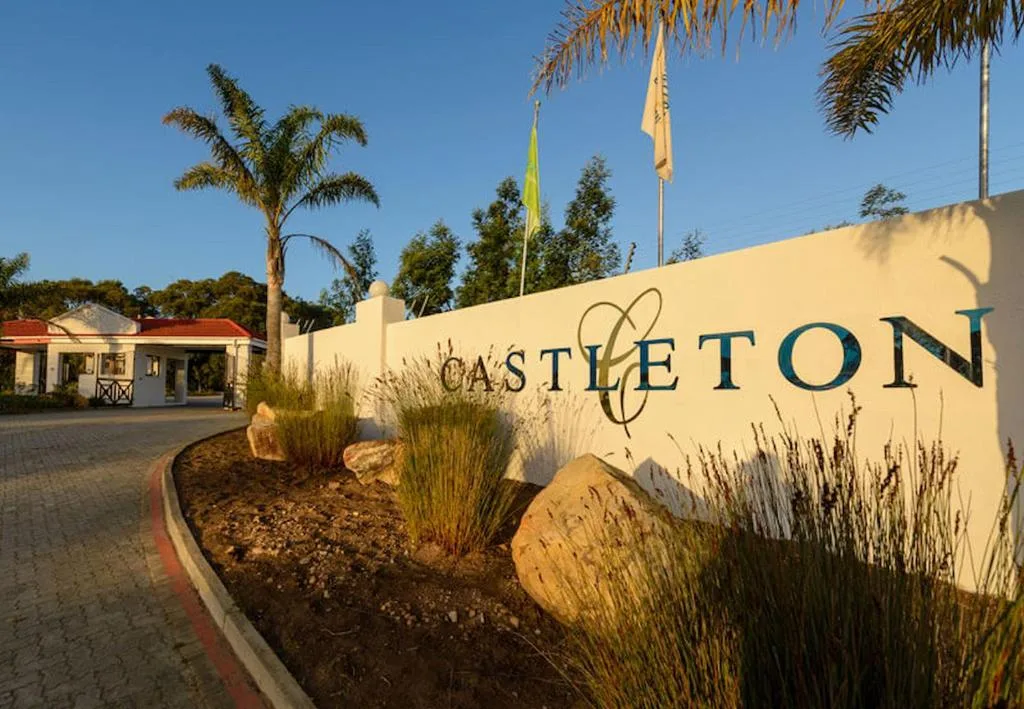 Castleton property entrance sign with landscaped garden and palm trees