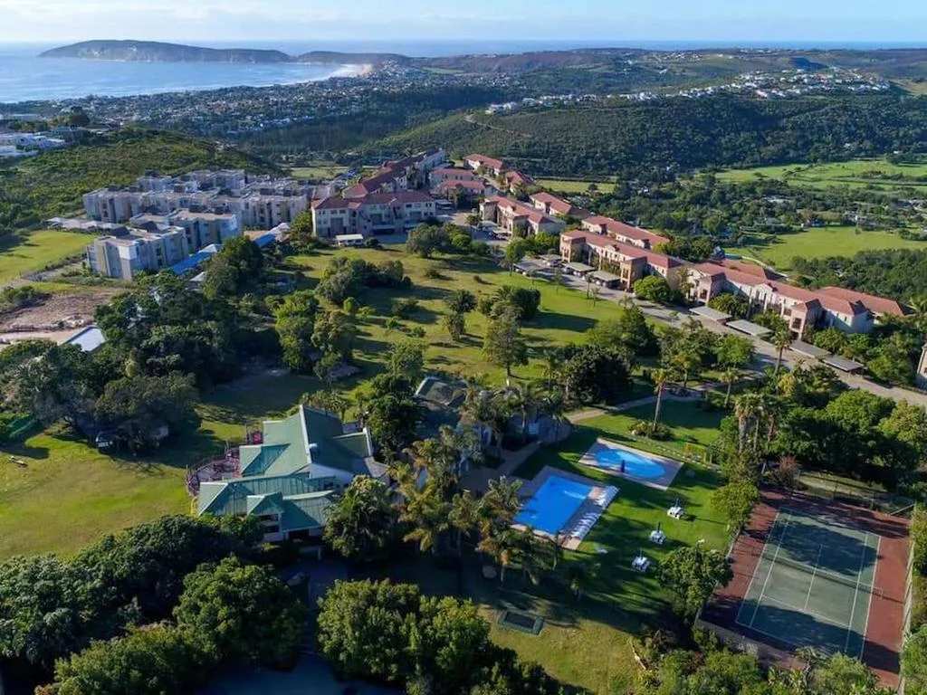 Aerial view of property with ocean, forest, and coastal town beyond