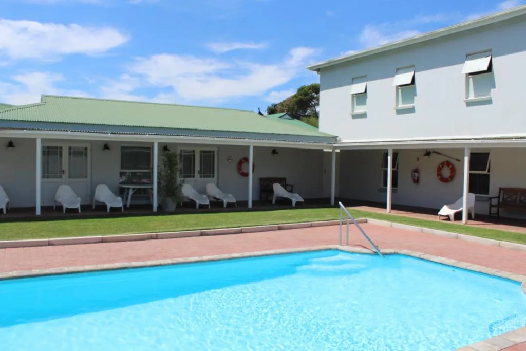 Bright blue swimming pool with brick patio and modern accommodation building