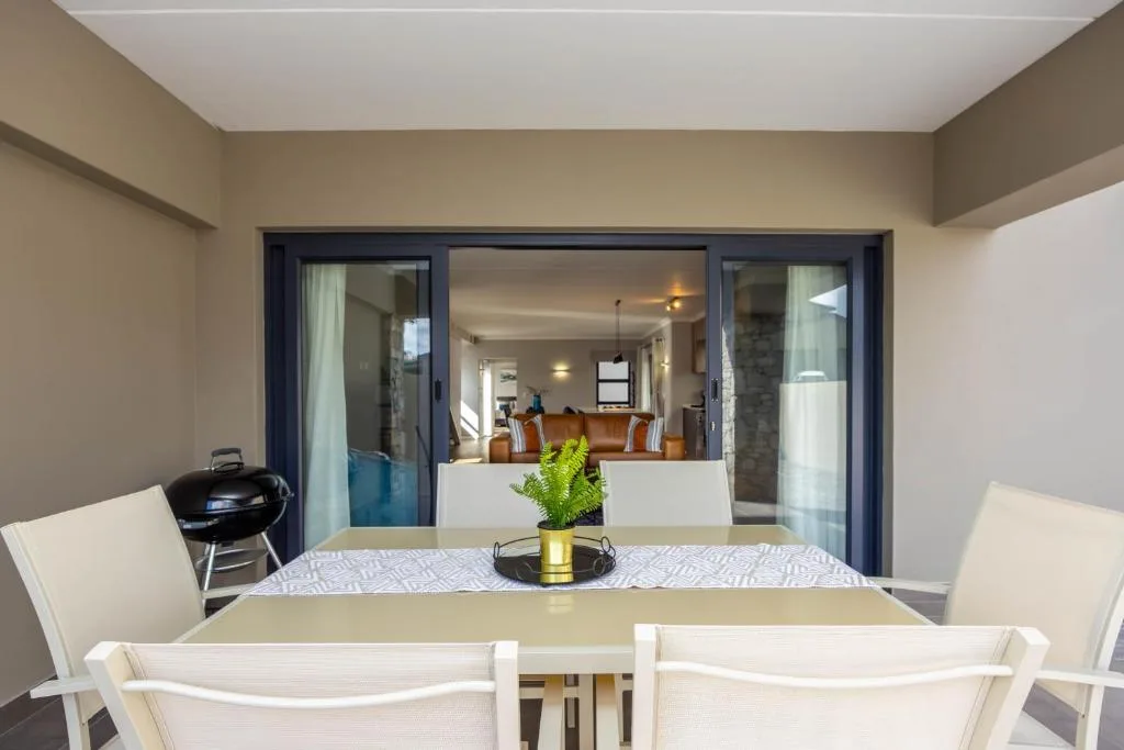 Modern dining table with white chairs overlooking open-plan living area