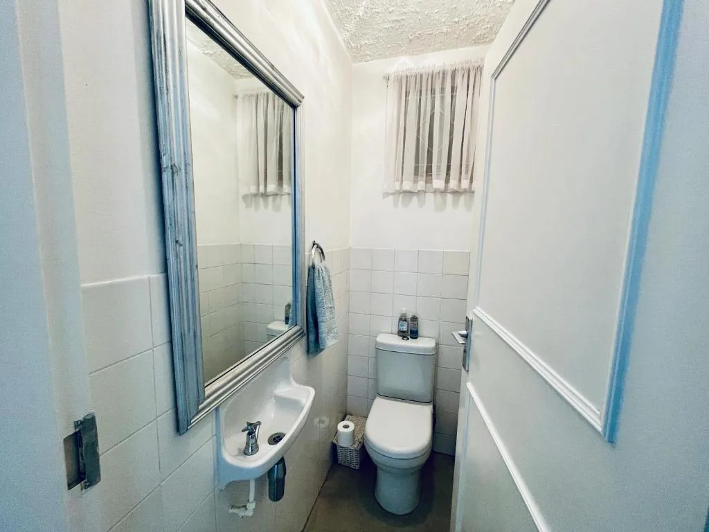Clean bathroom with toilet, sink, mirror, and tiled walls