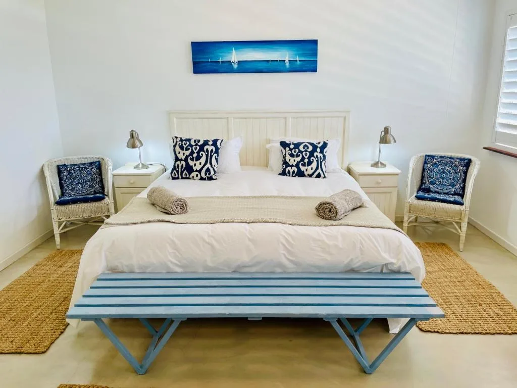 Coastal-themed bedroom with cream bed, navy patterned pillows, and blue striped bench