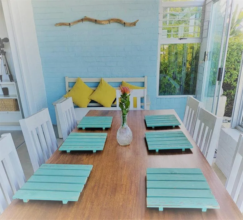 Bright dining room with turquoise placemats and yellow accent pillows
