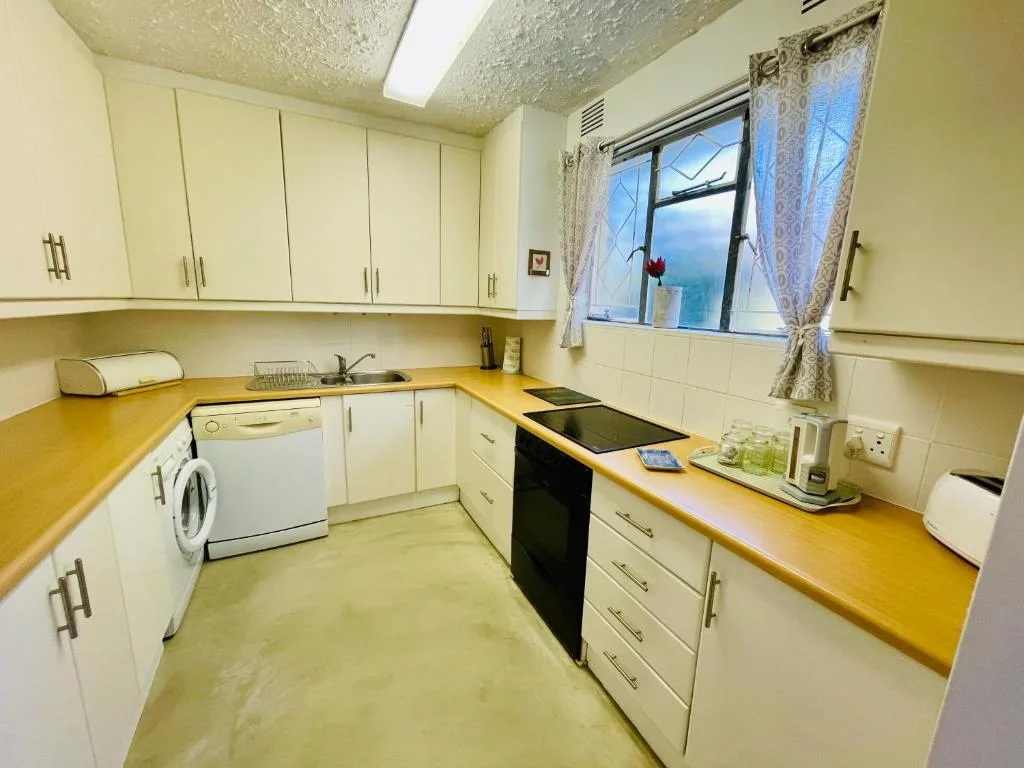 Compact kitchen with cream cabinets, yellow countertops, and stove