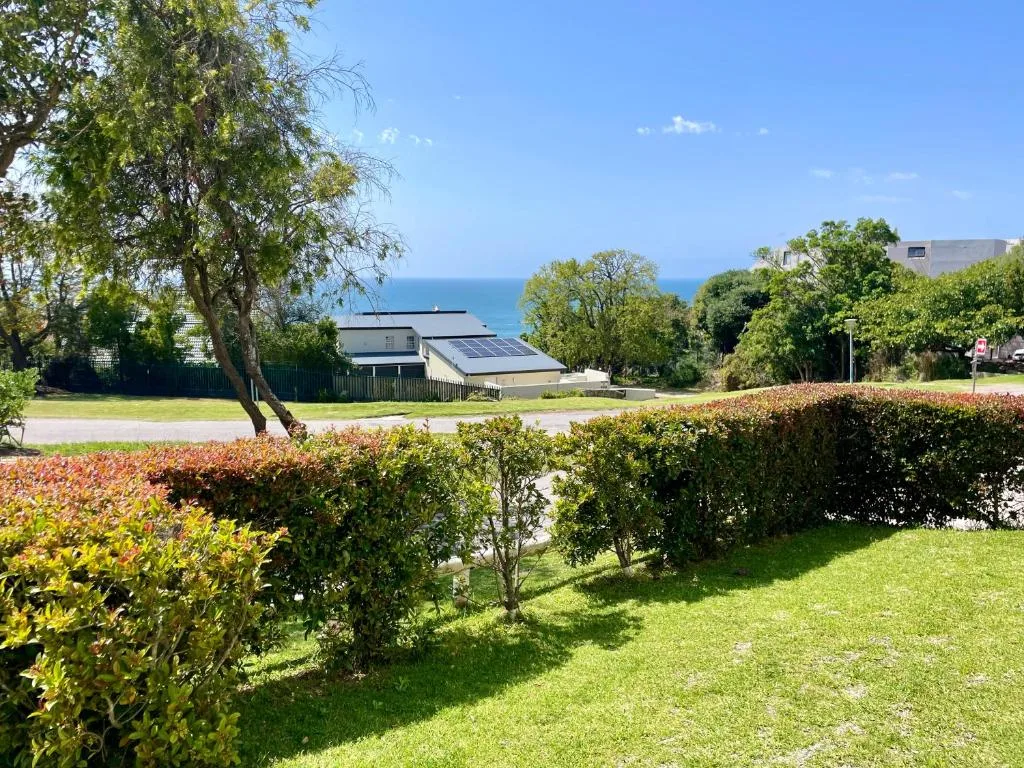 Ocean view across manicured gardens and neighboring properties, sea horizon visible