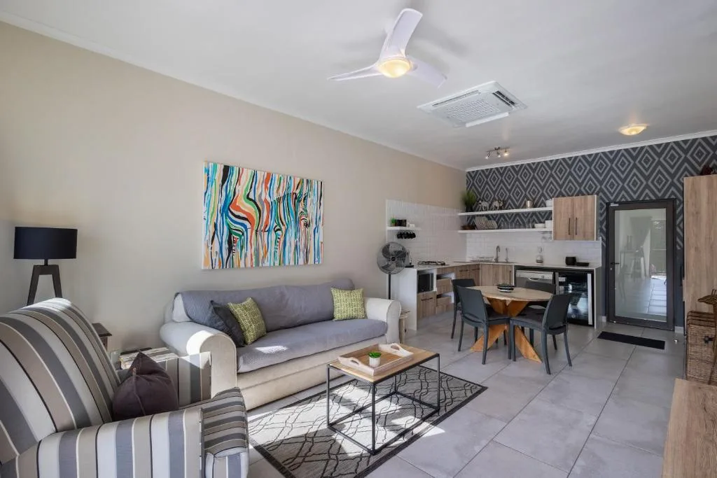 Open-plan lounge with grey sofa, striped armchair, and colorful wall art