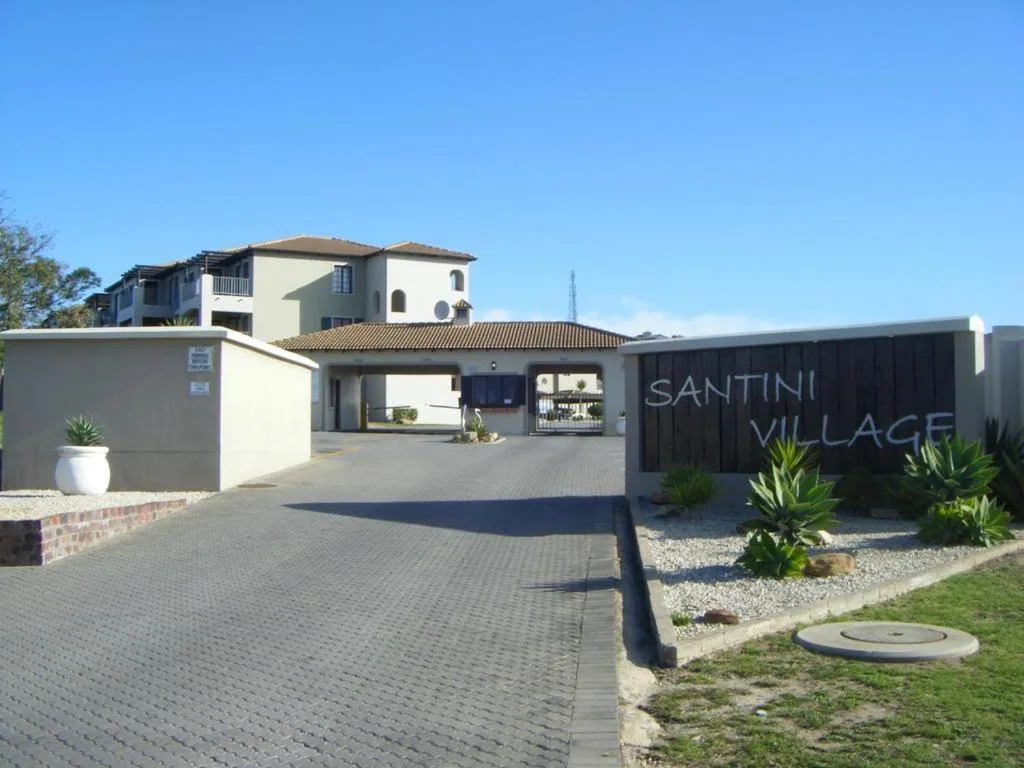 Modern cream and black villa entrance with paved driveway and signage