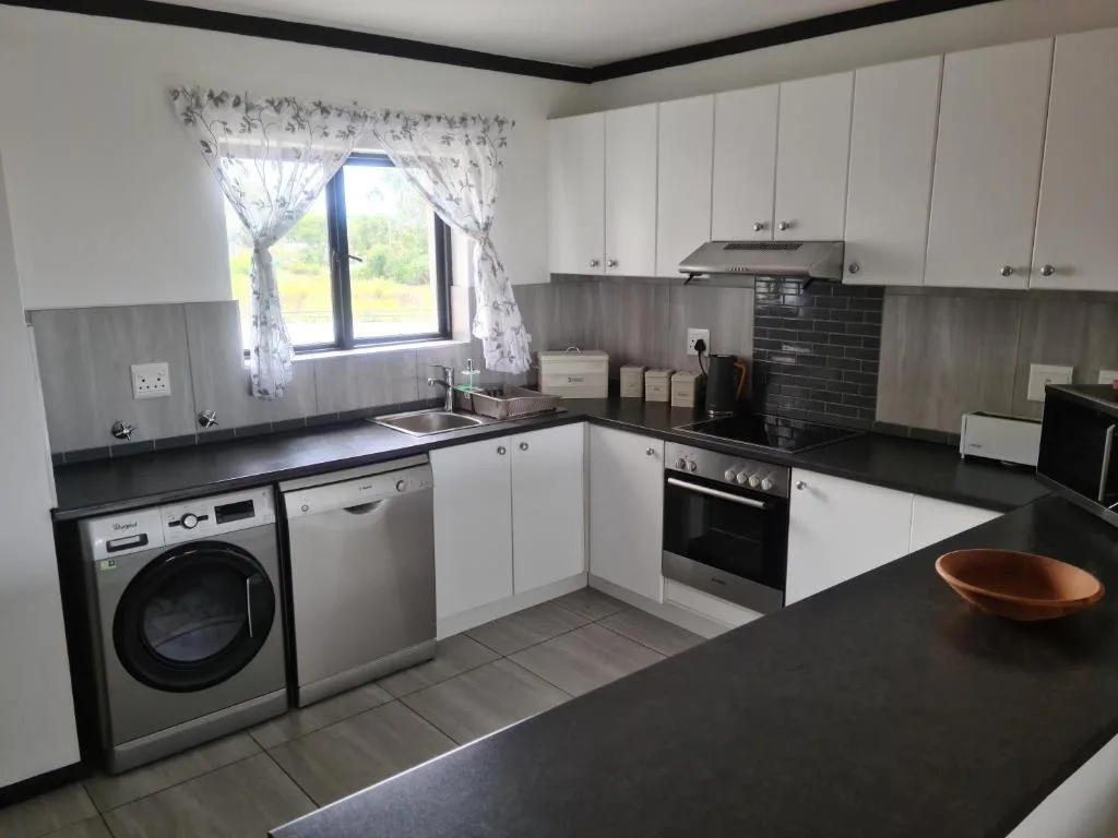 Modern kitchen with white cabinets, black countertops, and stainless steel appliances