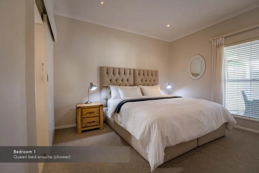 Spacious bedroom with queen bed, upholstered headboard, wooden nightstand